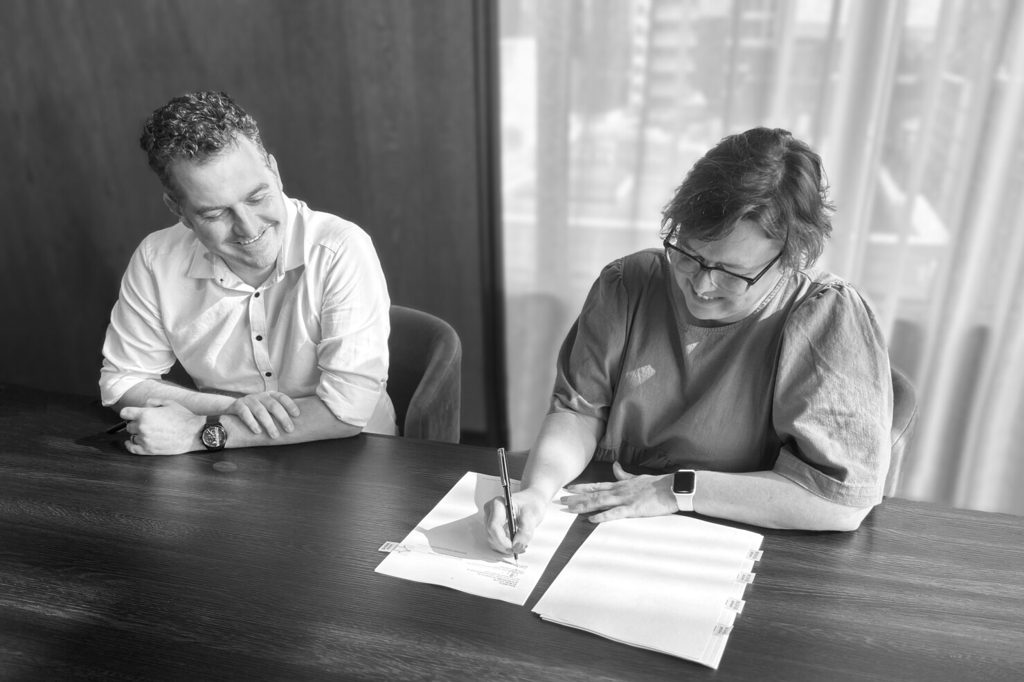 Ben Luppino watches Sonya Montgomerie signing contracts to accept her role as DesignInc Adelaide director